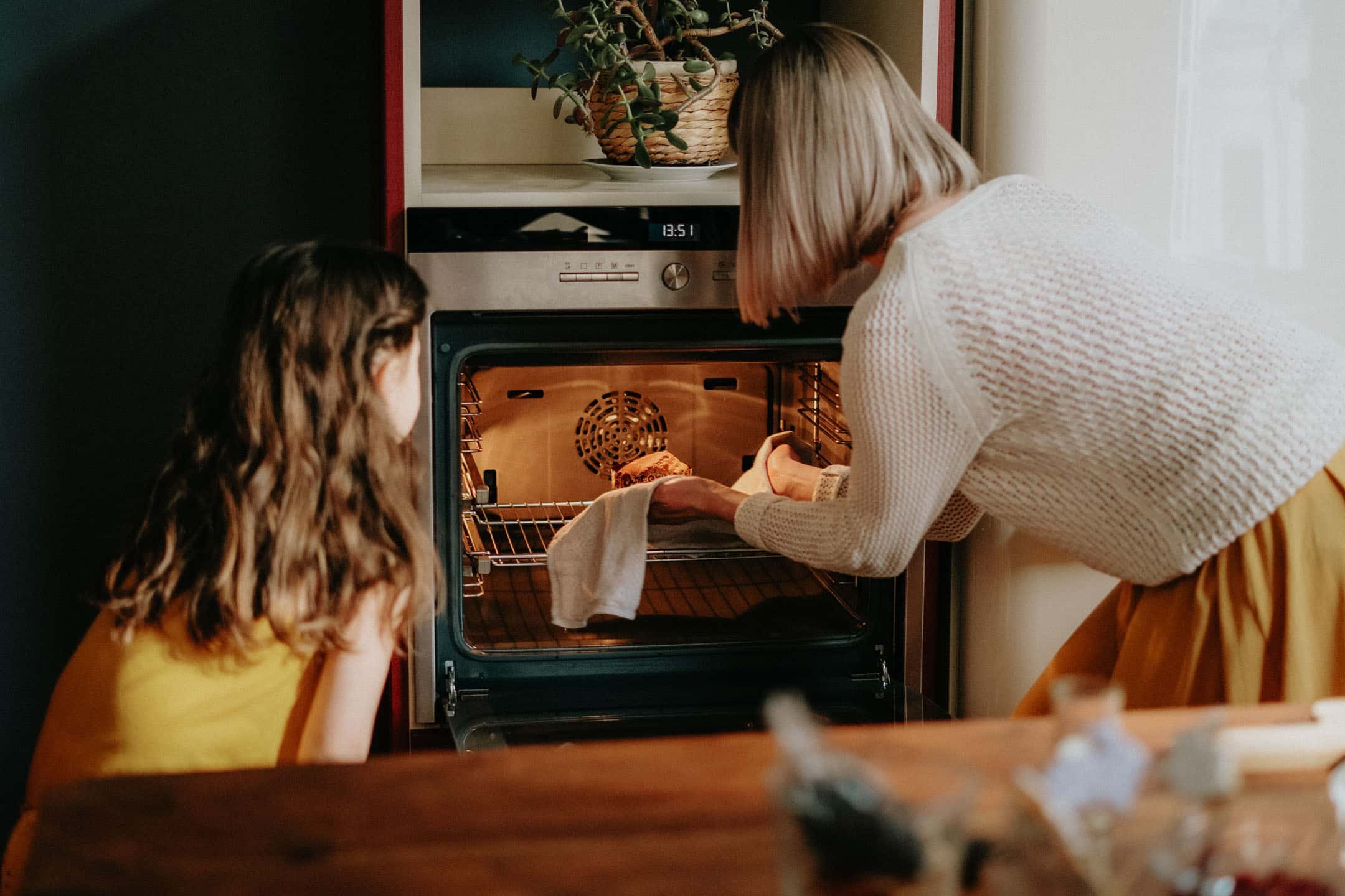 En kvinna och hennes dotter tar ut ett nybakat bröd från ugnen.